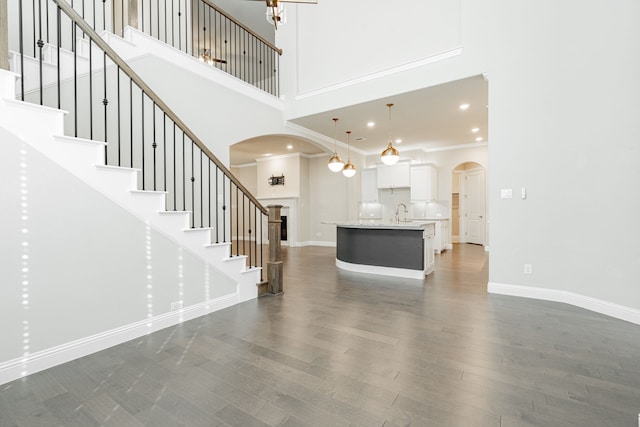 unfurnished living room featuring ornamental molding, dark hardwood / wood-style floors, and a towering ceiling