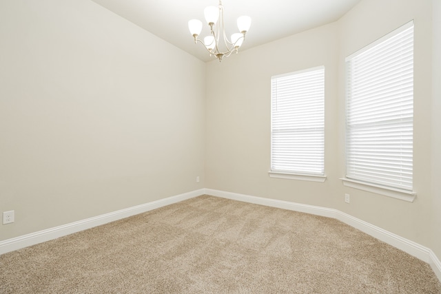 carpeted spare room featuring a notable chandelier