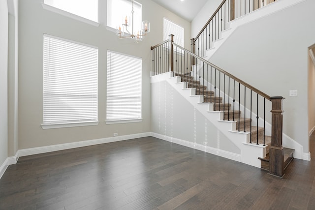 stairs featuring hardwood / wood-style flooring, a chandelier, and a towering ceiling