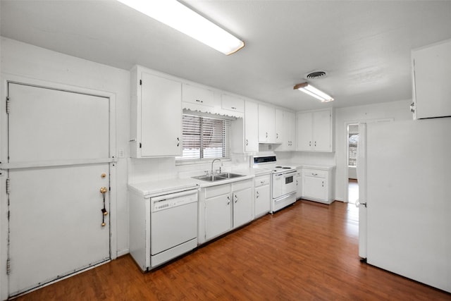 kitchen with white cabinetry, sink, backsplash, dark hardwood / wood-style flooring, and white appliances