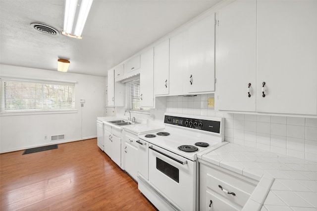 kitchen with sink, white cabinetry, light wood-type flooring, tile counters, and white appliances