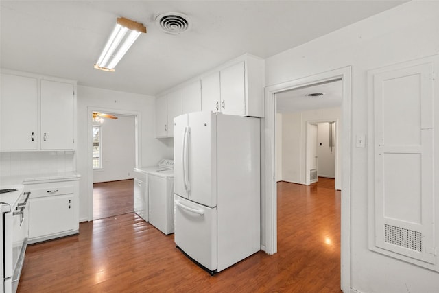 kitchen with hardwood / wood-style flooring, washer and clothes dryer, white cabinets, and white appliances