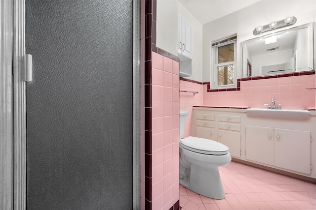 bathroom featuring tile patterned flooring, vanity, tile walls, and toilet