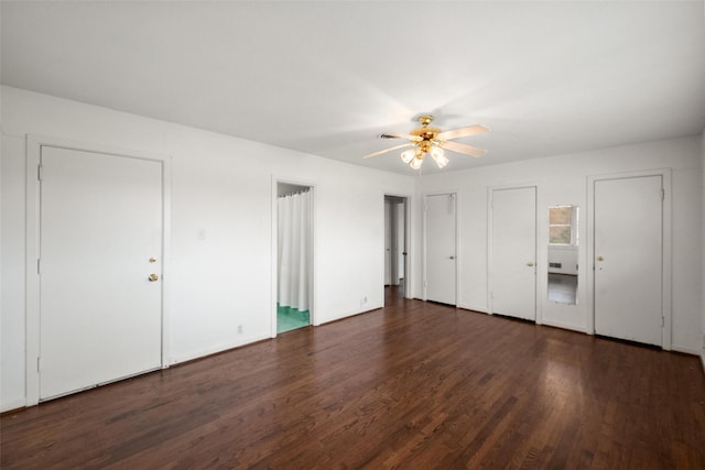 unfurnished bedroom featuring dark wood-type flooring, ceiling fan, and two closets