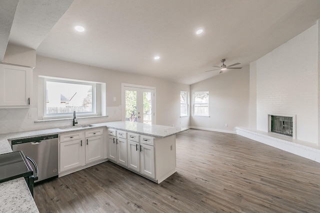 kitchen with sink, white cabinetry, light stone counters, a brick fireplace, and stainless steel dishwasher