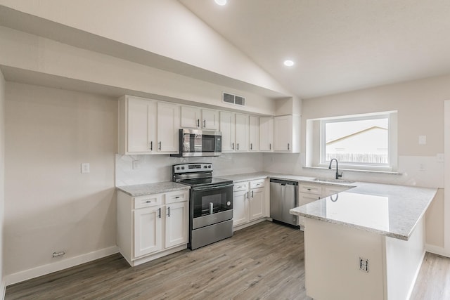 kitchen featuring lofted ceiling, stainless steel appliances, kitchen peninsula, and white cabinets