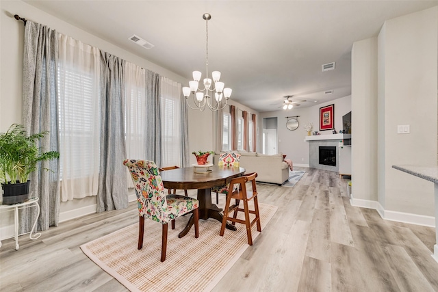 dining room with ceiling fan with notable chandelier and light hardwood / wood-style flooring