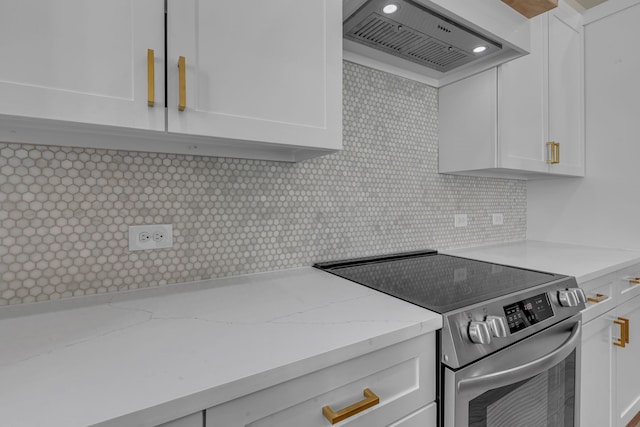 kitchen with light stone counters, stainless steel electric range, backsplash, white cabinets, and wall chimney range hood