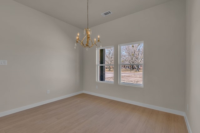 unfurnished room with a notable chandelier and light hardwood / wood-style floors