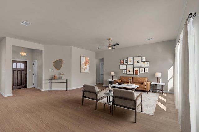 living room with ceiling fan with notable chandelier and light wood-type flooring