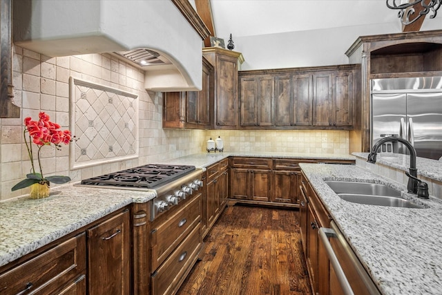 kitchen featuring dark wood-style floors, custom exhaust hood, stainless steel appliances, decorative backsplash, and a sink