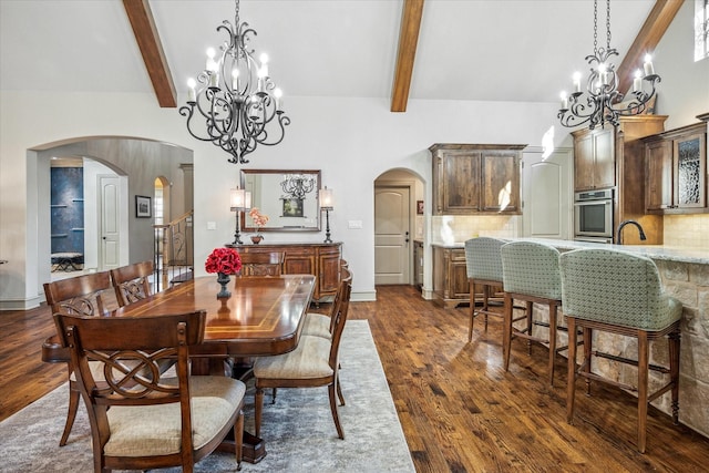 dining area featuring arched walkways, a chandelier, dark wood-style flooring, beamed ceiling, and high vaulted ceiling