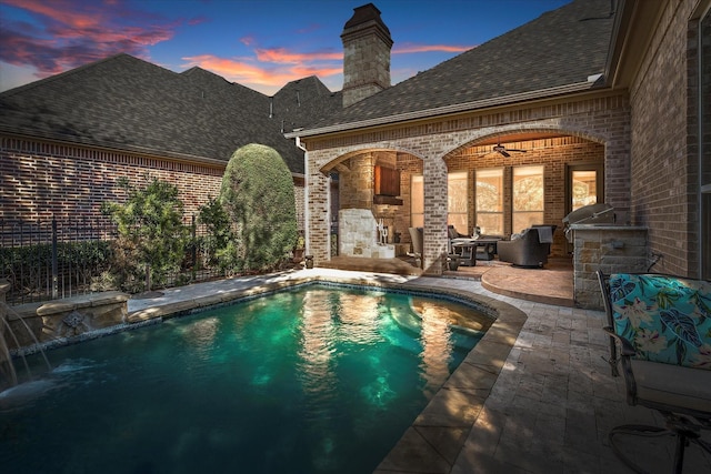 pool at dusk with ceiling fan, a patio, and an outdoor pool