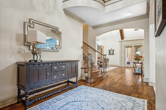 corridor featuring arched walkways, wood finished floors, stairs, and baseboards