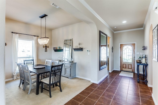 dining room featuring an inviting chandelier, dark tile patterned flooring, and ornamental molding