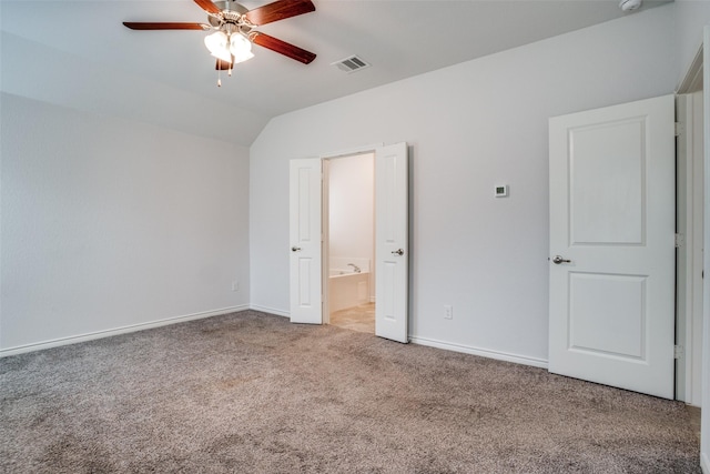 unfurnished bedroom featuring ensuite bath, vaulted ceiling, ceiling fan, and carpet flooring