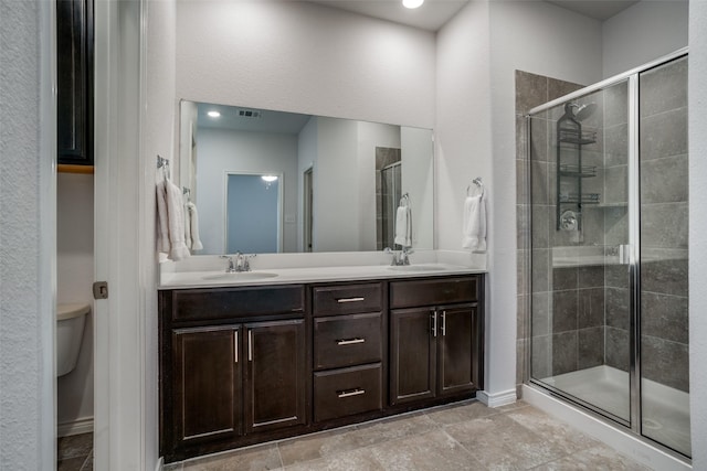 bathroom featuring vanity, a shower with shower door, and toilet