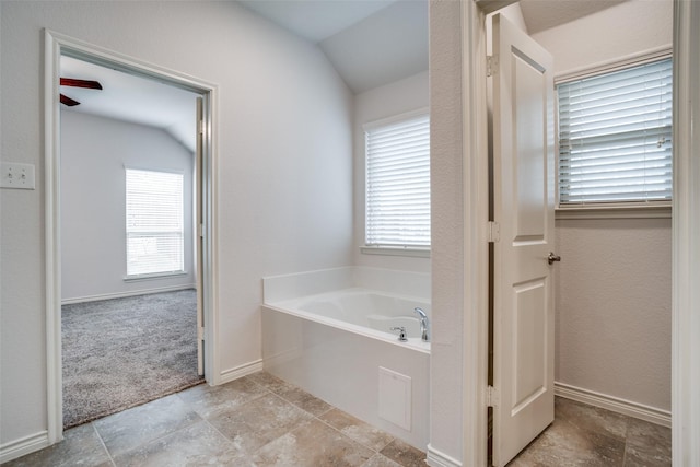 bathroom with plenty of natural light, vaulted ceiling, and a tub