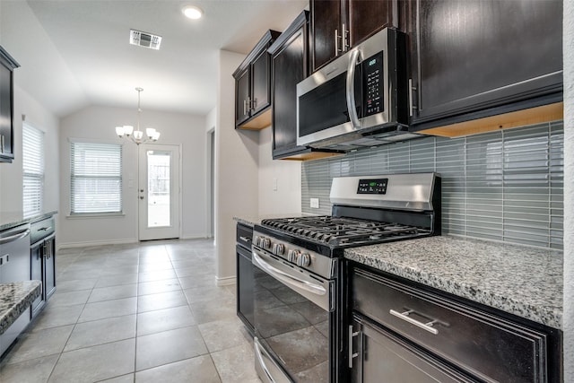 kitchen featuring lofted ceiling, tasteful backsplash, light stone counters, decorative light fixtures, and appliances with stainless steel finishes