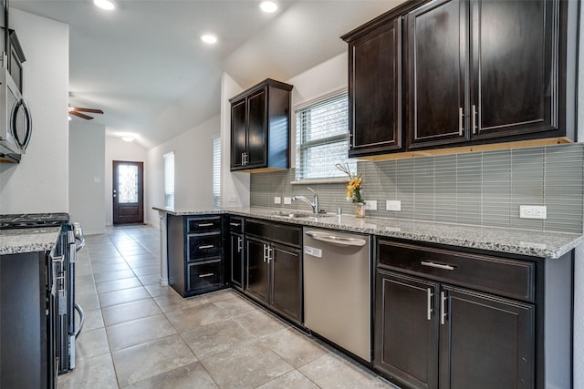 kitchen with light stone counters, appliances with stainless steel finishes, vaulted ceiling, and backsplash