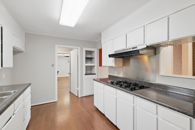 kitchen featuring black gas cooktop, under cabinet range hood, dark wood-type flooring, white cabinets, and dark countertops