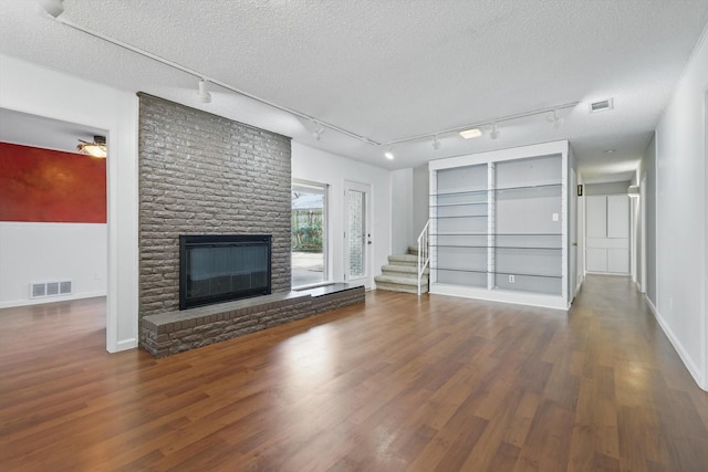 unfurnished living room featuring a fireplace, wood finished floors, and visible vents