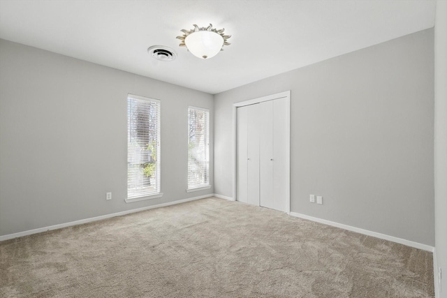 unfurnished bedroom featuring a closet, carpet, visible vents, and baseboards