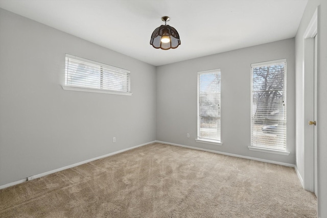 carpeted spare room featuring plenty of natural light and baseboards