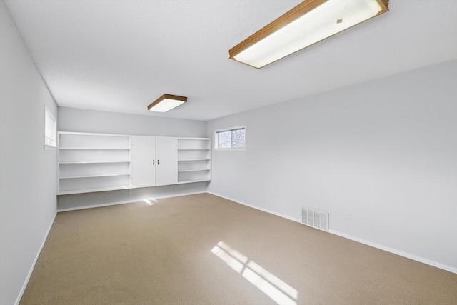 carpeted empty room featuring baseboards and visible vents