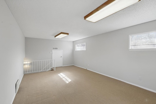 spare room with carpet, visible vents, and baseboards