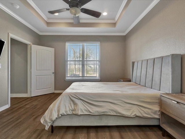 bedroom featuring crown molding, dark hardwood / wood-style flooring, and a tray ceiling