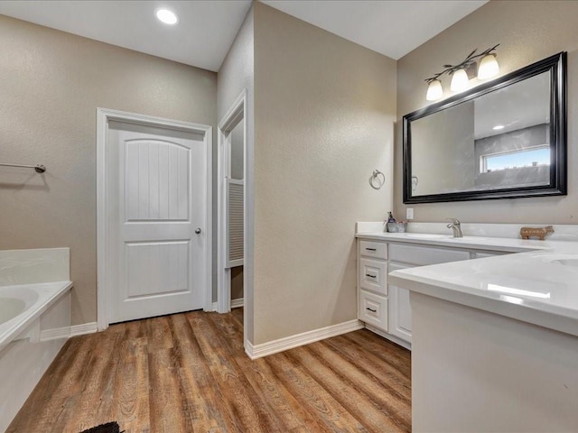 bathroom featuring wood-type flooring, vanity, and a washtub