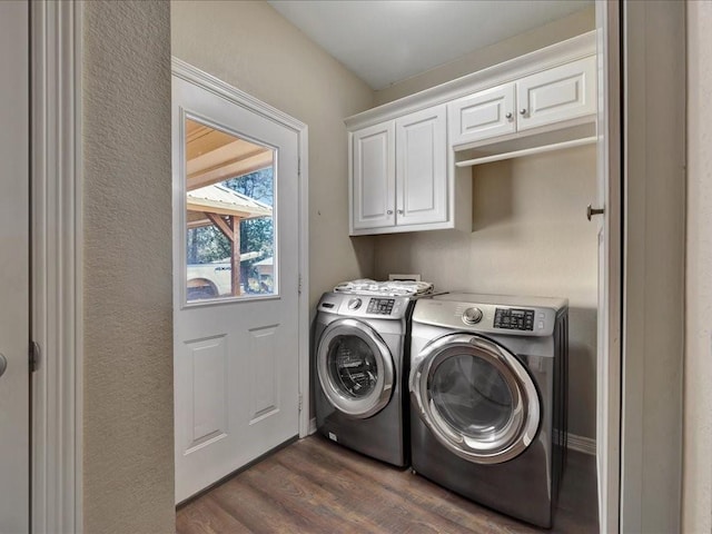 washroom with dark wood-type flooring, washer and clothes dryer, and cabinets