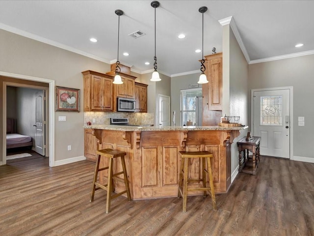 kitchen with a breakfast bar area, decorative light fixtures, dark hardwood / wood-style floors, kitchen peninsula, and light stone countertops