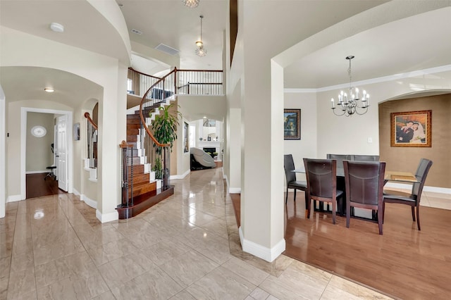 entryway featuring crown molding, a towering ceiling, and a notable chandelier