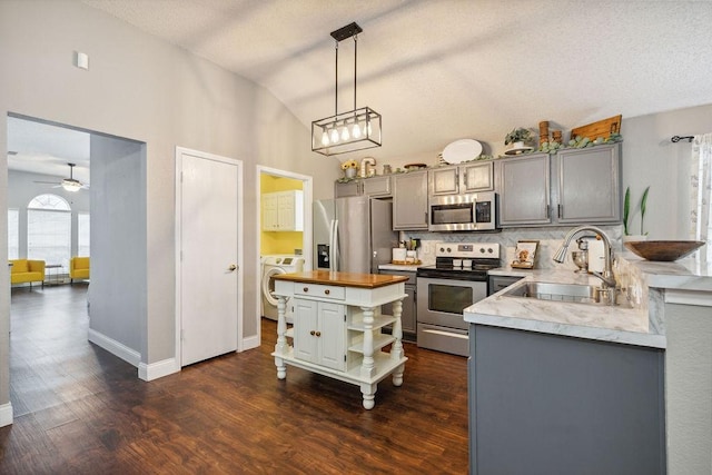 kitchen featuring pendant lighting, washer / clothes dryer, sink, wooden counters, and stainless steel appliances