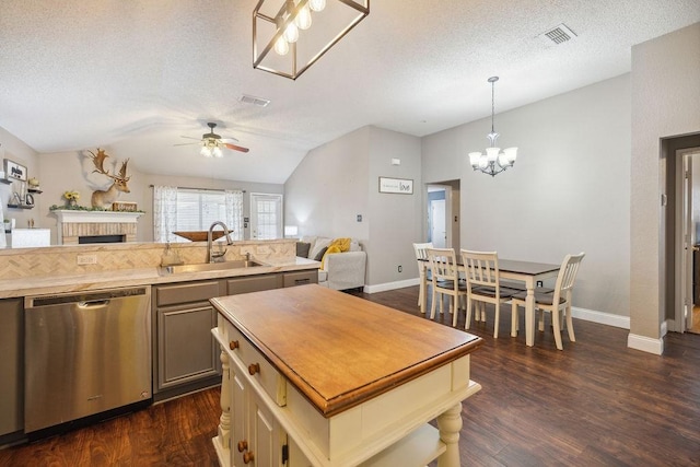 kitchen with dark wood-type flooring, lofted ceiling, sink, decorative light fixtures, and stainless steel dishwasher