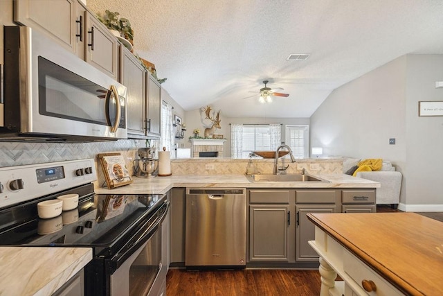 kitchen with lofted ceiling, sink, ceiling fan, stainless steel appliances, and decorative backsplash