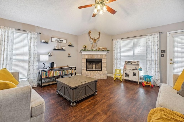 living room featuring dark wood-type flooring, vaulted ceiling, a textured ceiling, ceiling fan, and a fireplace