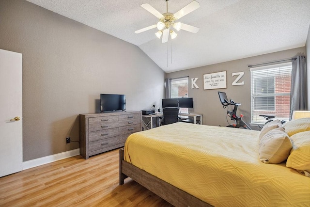 bedroom with ceiling fan, vaulted ceiling, a textured ceiling, and light wood-type flooring