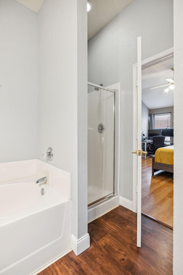 bathroom with wood-type flooring, independent shower and bath, and a textured ceiling