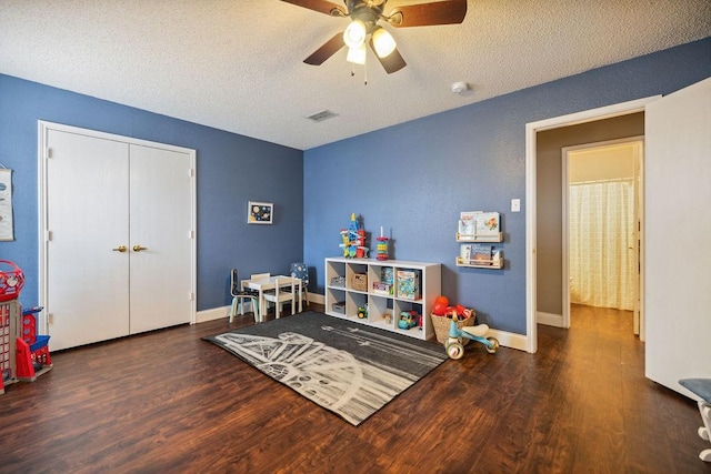 playroom with dark hardwood / wood-style flooring, ceiling fan, and a textured ceiling