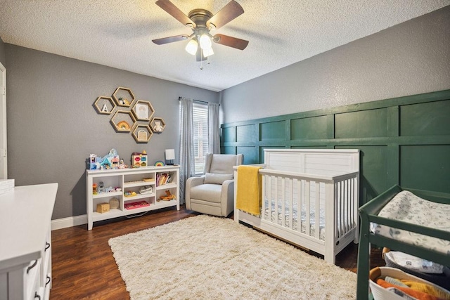 bedroom featuring ceiling fan, dark hardwood / wood-style flooring, a textured ceiling, and a crib