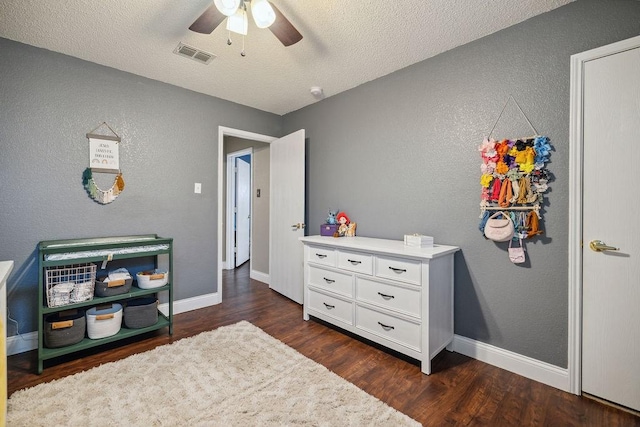 bedroom with ceiling fan, a textured ceiling, and dark hardwood / wood-style flooring