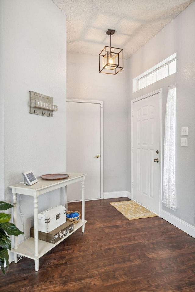 entryway with dark wood-type flooring and a textured ceiling