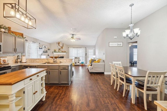 kitchen featuring ceiling fan with notable chandelier, pendant lighting, sink, gray cabinetry, and dark hardwood / wood-style flooring