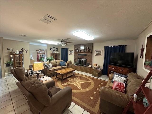 tiled living room with a brick fireplace, a textured ceiling, and ceiling fan