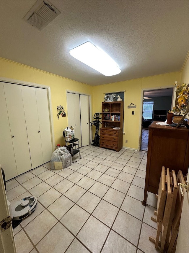 bedroom with two closets, a textured ceiling, and light tile patterned flooring