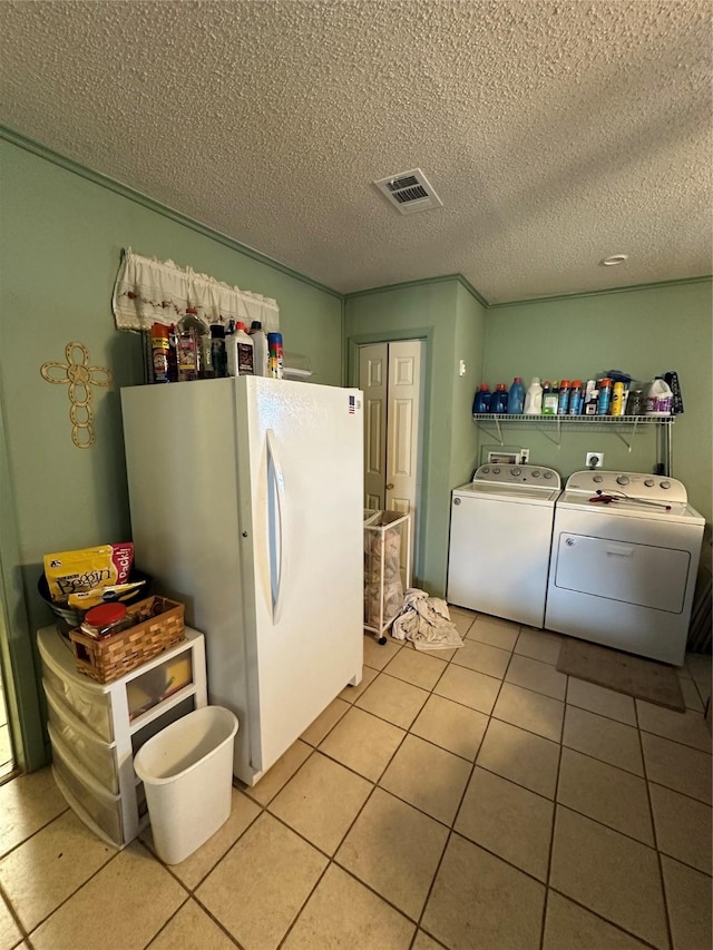 interior space with white fridge, light tile patterned floors, separate washer and dryer, and a textured ceiling