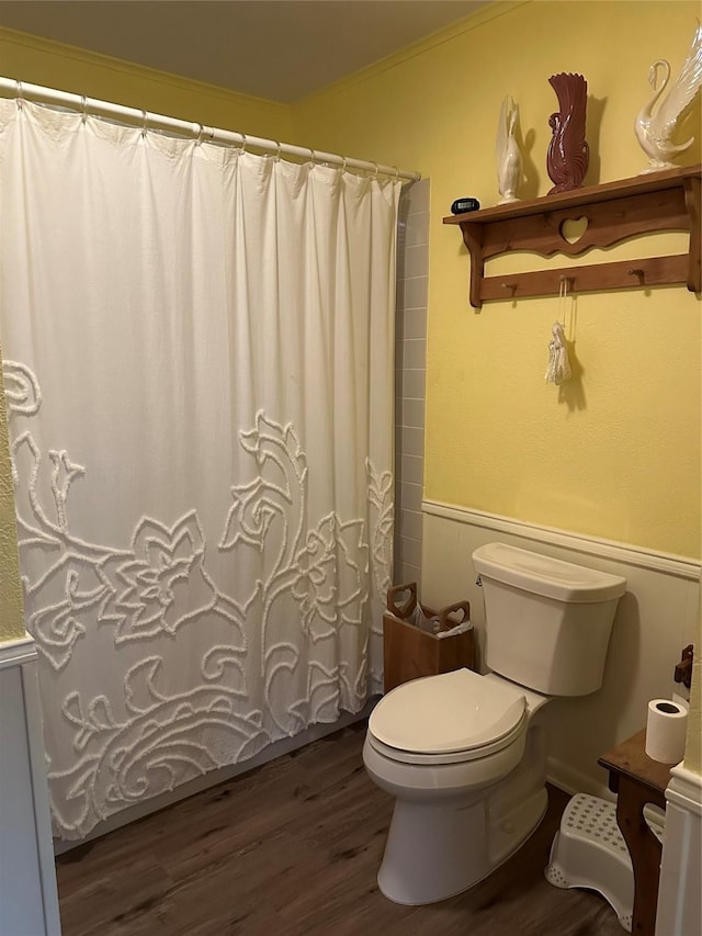 bathroom with a shower with curtain, hardwood / wood-style flooring, crown molding, and toilet